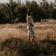 Zwangere vrouw in het avondlicht tussen het gras