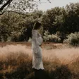 Zwangere vrouw in kanten jurk in een zonnig veld
